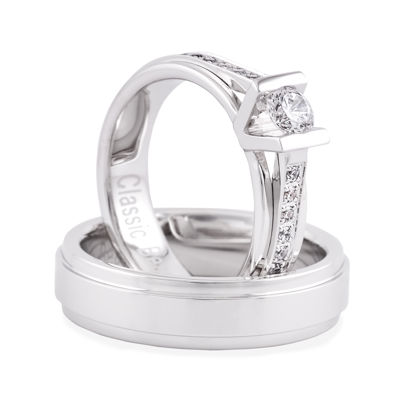 Een klassieke schoonheid mag deze ring absoluut genoemd worden. In de damesring een royale 0.33 CRT briljant ondersteund met elegante kleinere briljanten in de scheen.